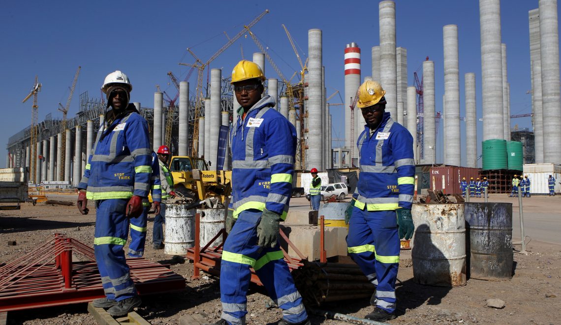 Workers are seen in front the construction site of Eskom's Medupi power station, a new dry-cooled coal fired power station, in Limpopo province, June 8, 2012. South African power utility Eskom reported a nearly 60 percent rise in full-year profit on Thursday owing to higher tariffs and said it would meet power demand during the winter, despite tight supplies. State-owned Eskom, which supplies 95 percent of South Africa's power, said profit in the year to end-March rose to 13.2 billion rand($1.58 billion) from 8.4 billion the previous year. Picture taken June 8, 2012. REUTERS/Siphiwe Sibeko (SOUTH AFRICA - Tags: ENVIRONMENT ENERGY BUSINESS)